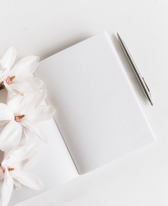 Image d'un livre avec deux pages blanches et des fleurs sur les côtés
